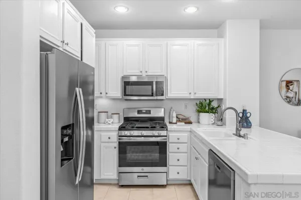 a kitchen with white cabinets and stainless steel appliances