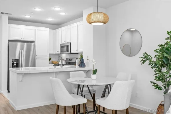 a kitchen with stainless steel appliances granite countertop a dining table chairs and a refrigerator