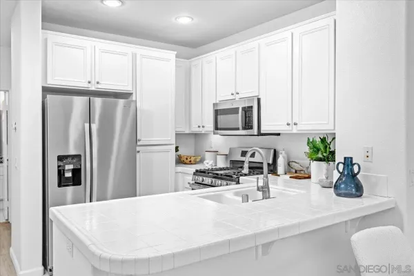 a kitchen with stainless steel appliances a white refrigerator cabinets a sink a stove and a window
