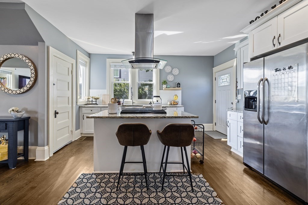 35 Jackson Street Saugus, MA 01906 - Photo 8 of 26 a kitchen with stainless steel appliances granite countertop a refrigerator a sink a stove a dining table and chairs with wooden floor