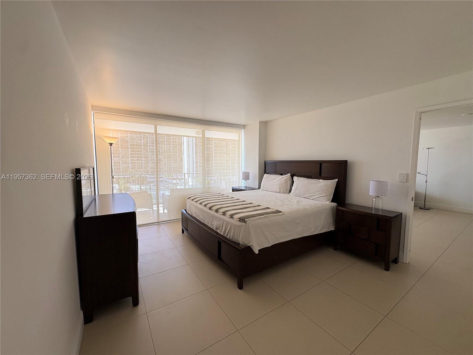 1865 Brickell Avenue, Unit A810 Miami, FL 33129 - Photo 15 of 24 a bedroom with a bed lamp and a large window