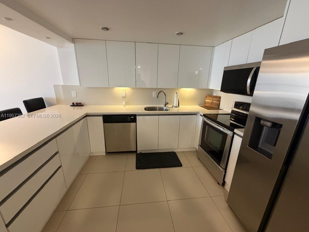 1865 Brickell Avenue, Unit A810 Miami, FL 33129 - Photo 4 of 24 a kitchen with a sink stainless steel appliances and white cabinets