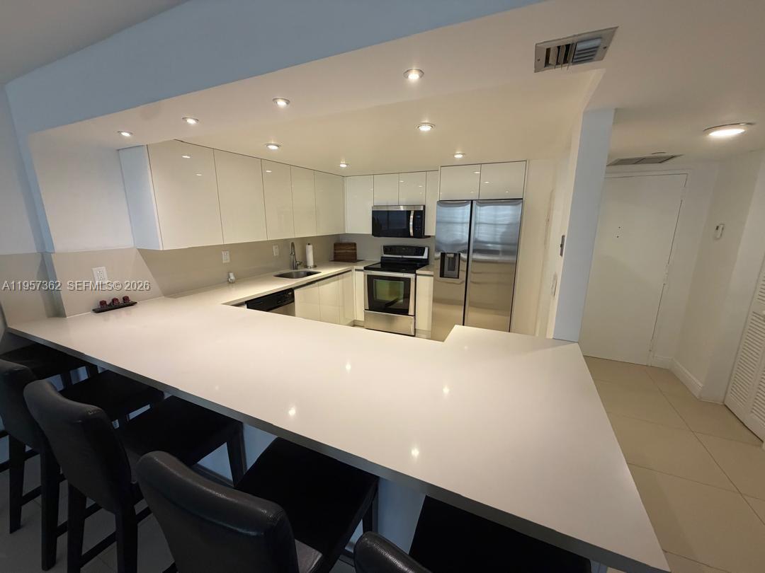1865 Brickell Avenue, Unit A810 Miami, FL 33129 - Photo 5 of 24 a kitchen with kitchen island a sink dishwasher a stove and a refrigerator with wooden floor