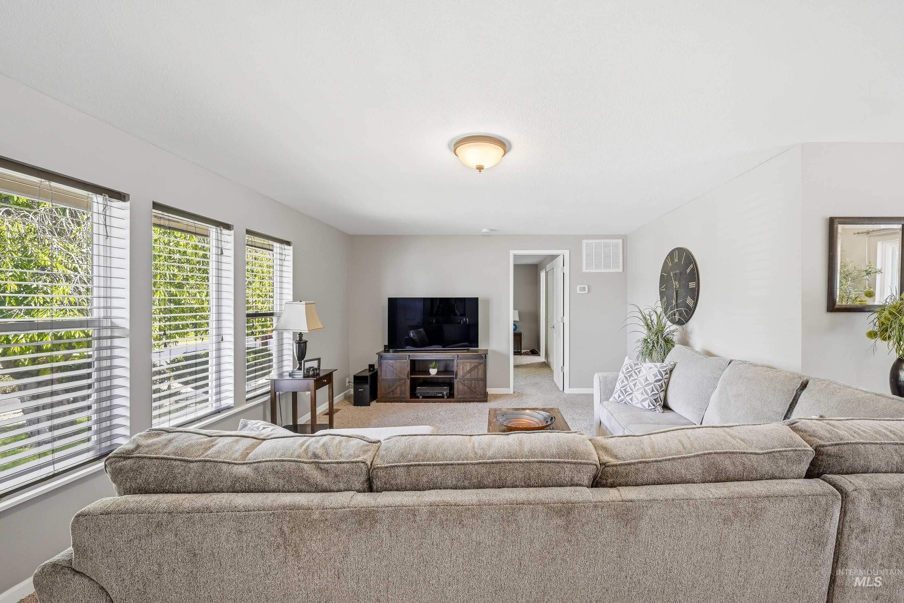 3715 18th Street Lewiston, ID 83501 - Photo 7 of 30 Spacious living area featuring light gray walls, carpet flooring, and three large windows with horizontal blinds
