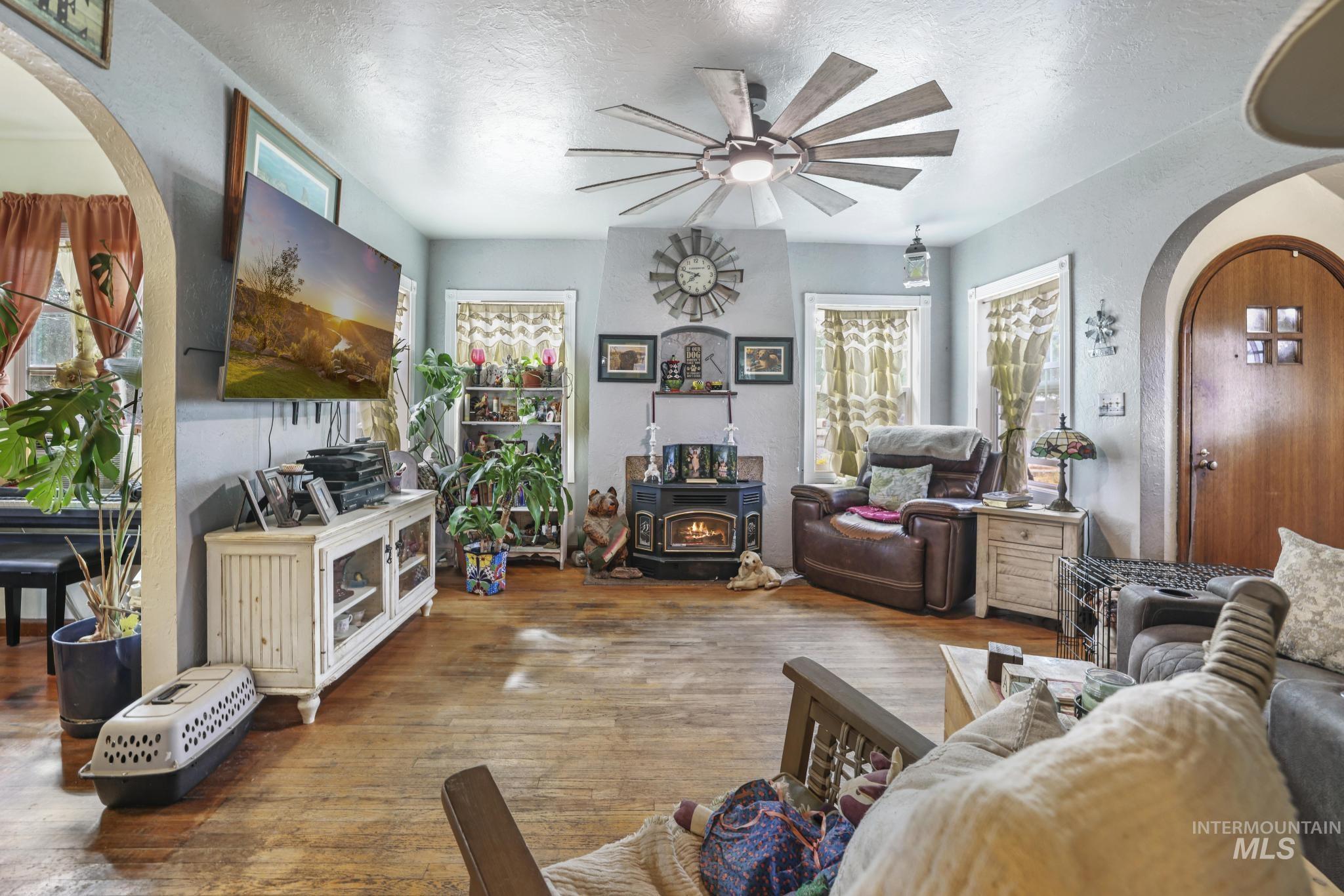 602 4th Avenue East Gooding, ID 83330 - Photo 4 of 36 Living room with arched walkways, wood finished floors, a wood stove, a textured ceiling, and healthy amount of natural light
