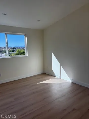 a view of an empty room with a window and wooden floor