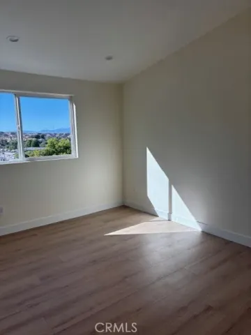 a view of an empty room with a window and wooden floor