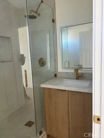 a bathroom with a granite countertop sink a mirror and shower