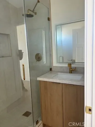 a bathroom with a granite countertop sink a mirror and shower