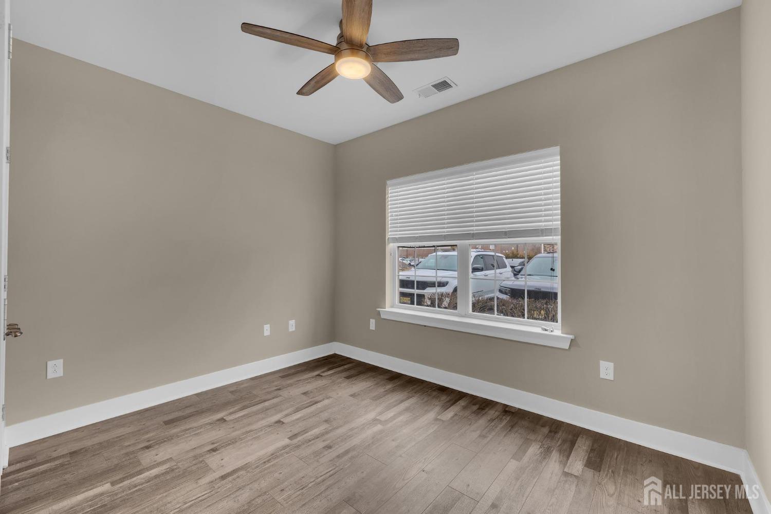 415 Tavern Road Monroe Township, NJ 08831 - Photo 12 of 39 an empty room with wooden floor ceiling fan and windows