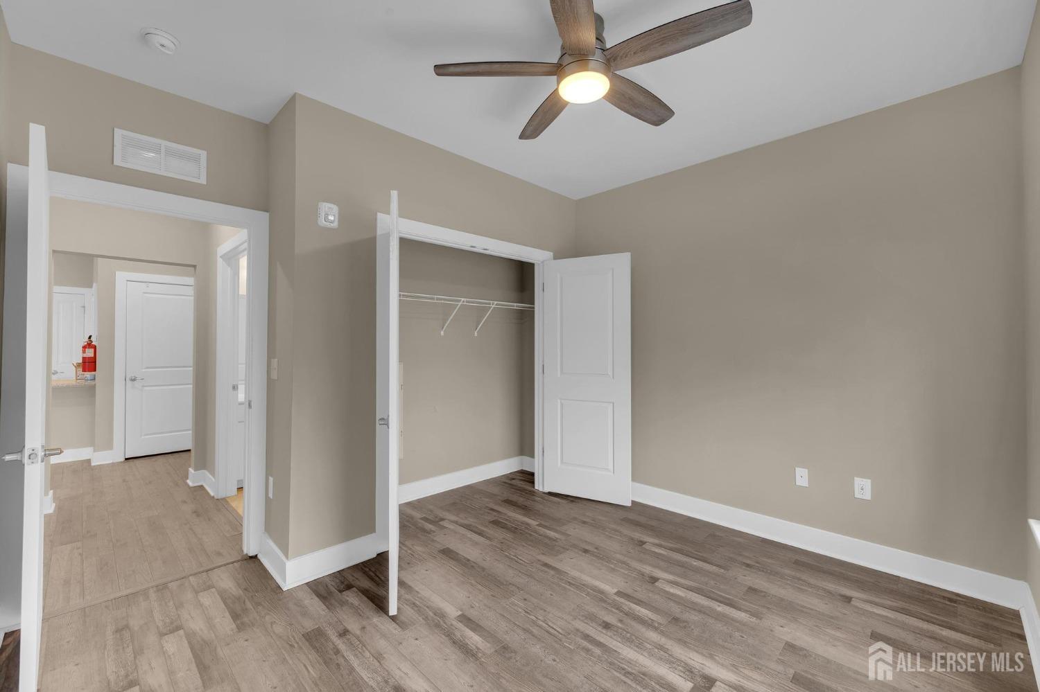 415 Tavern Road Monroe Township, NJ 08831 - Photo 7 of 39 an empty room with wooden floor and ceiling fan