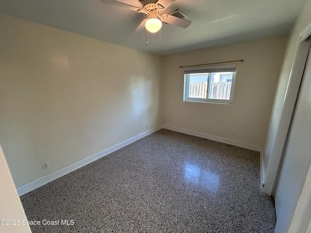 an empty room with a chandelier fan and windows