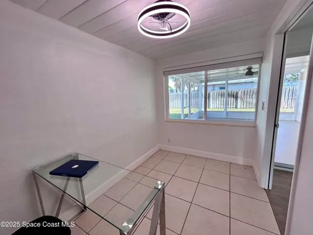an empty room with a chandelier fan and windows