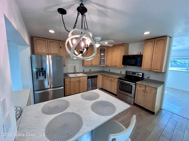 a kitchen with stainless steel appliances granite countertop a sink a stove a refrigerator cabinets and chairs