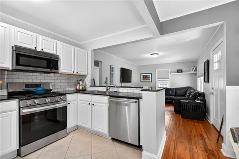 a kitchen with stainless steel appliances granite countertop a stove top oven a sink dishwasher a refrigerator and a microwave oven with wooden floor