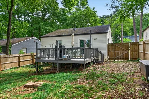 a view of a house with a yard chairs and wooden fence