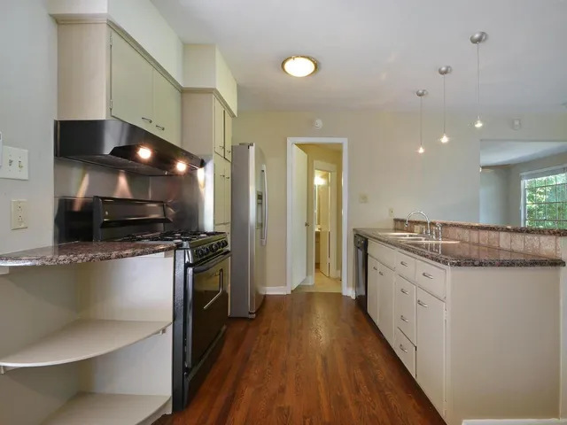 a kitchen with stainless steel appliances kitchen island granite countertop a stove a sink and a refrigerator