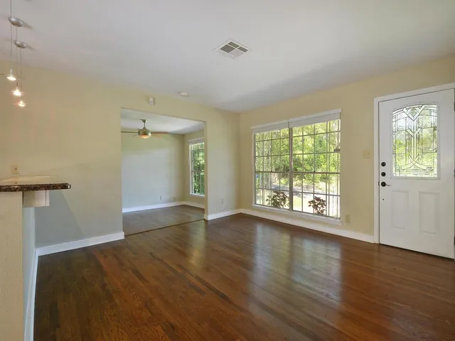an empty room with wooden floor and windows