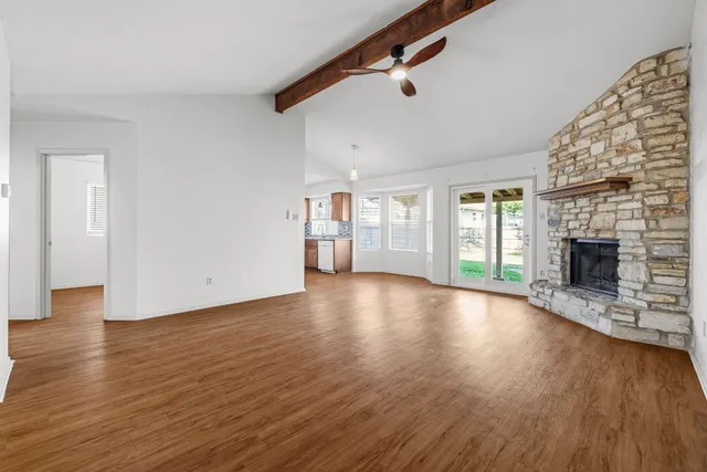 an empty room with wooden floor fireplace and windows