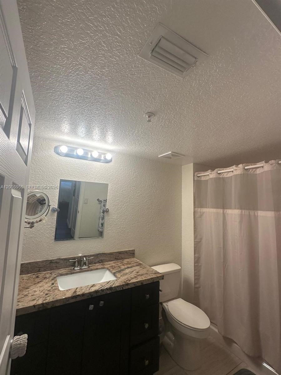6920 West Sample Road, Unit 6920 Pompano Beach, FL 33063 - Photo 13 of 30 a bathroom with a granite countertop sink toilet and a mirror