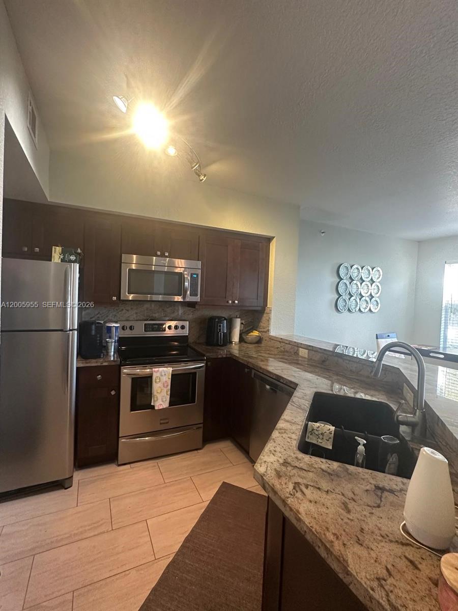 6920 West Sample Road, Unit 6920 Pompano Beach, FL 33063 - Photo 16 of 30 a kitchen with granite countertop stainless steel appliances and wooden cabinets