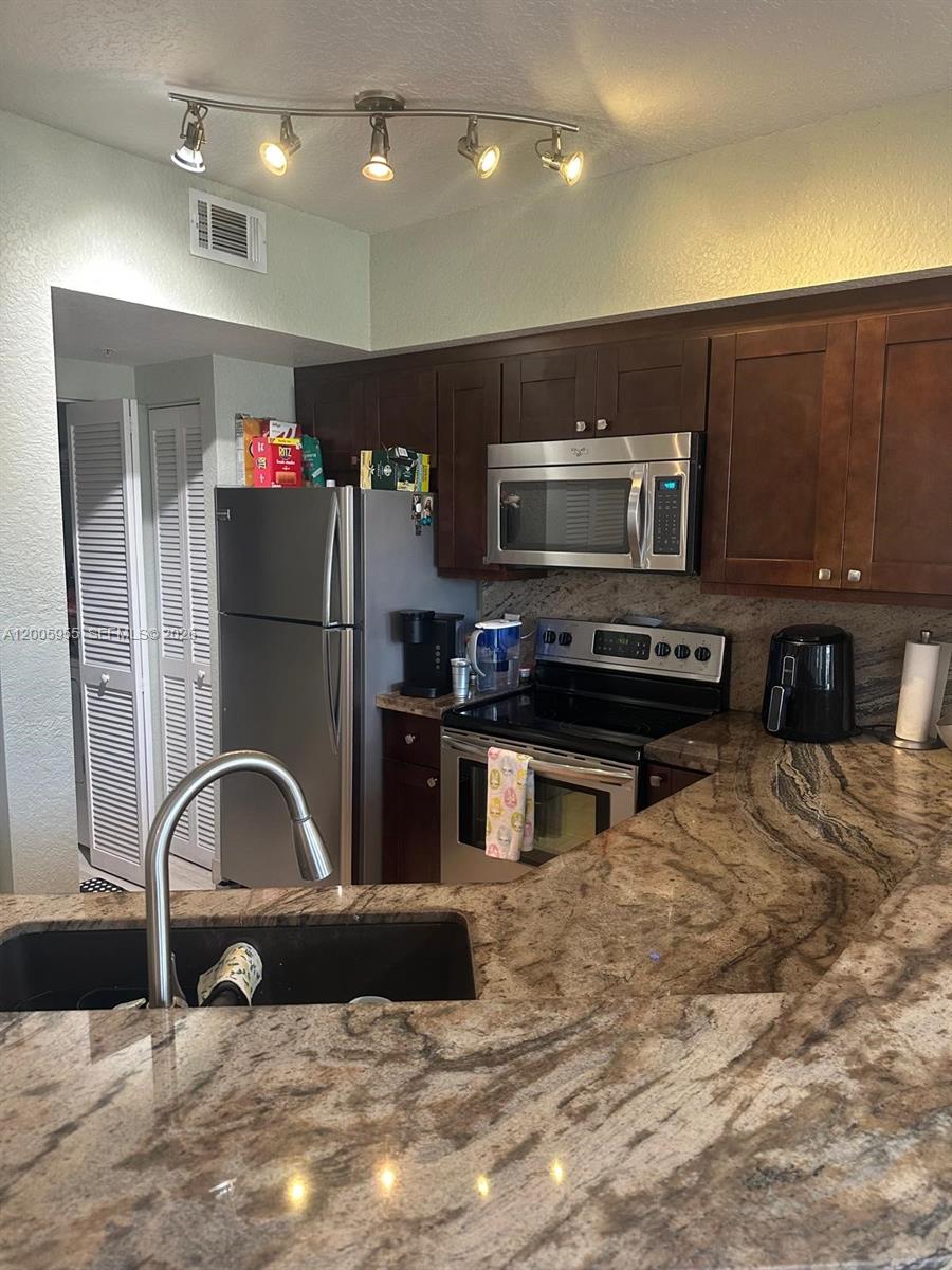 6920 West Sample Road, Unit 6920 Pompano Beach, FL 33063 - Photo 17 of 30 a kitchen with kitchen island stainless steel appliances a sink and a microwave