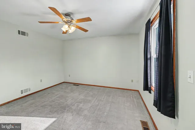 a view of an empty room and window with hardwood floor