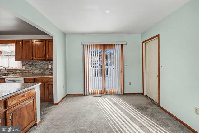 an empty room with a window and chandelier fan