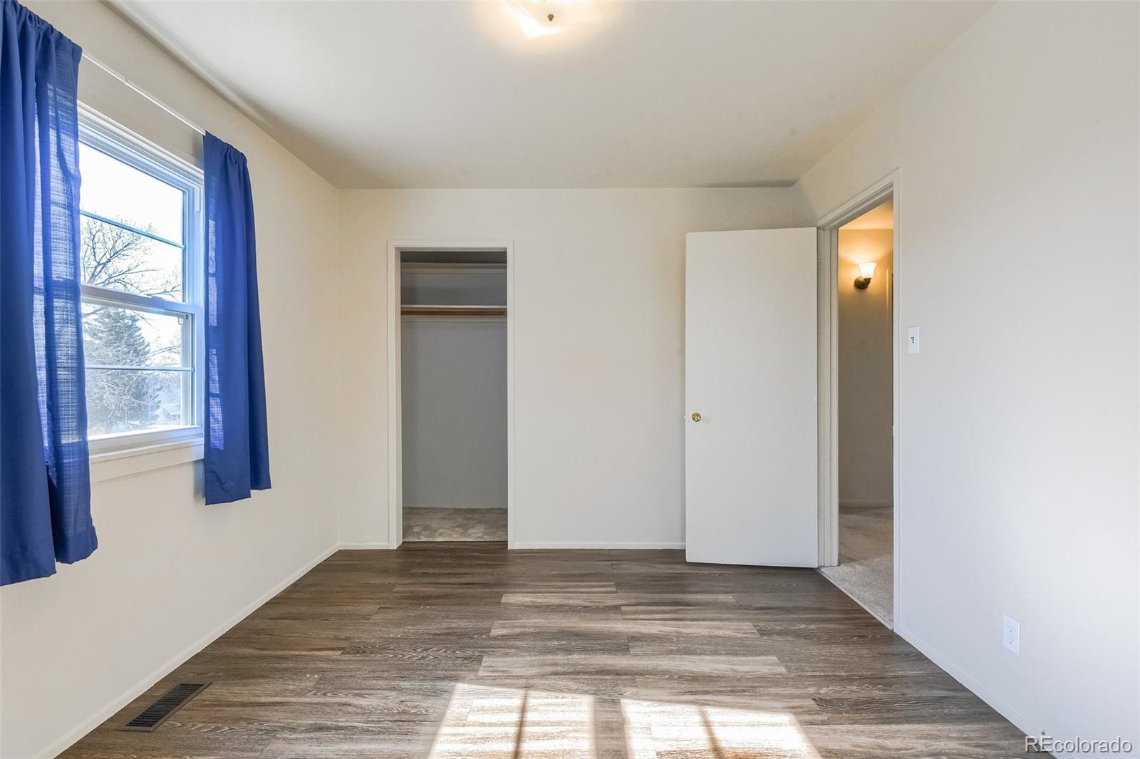 8941 Lilly Drive Thornton, CO 80229 - Photo 19 of 27 a view of an empty room with wooden floor and windows