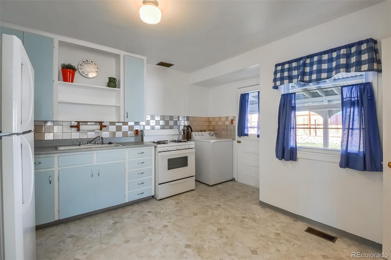 8941 Lilly Drive Thornton, CO 80229 - Photo 9 of 27 a kitchen with white cabinets and white appliances