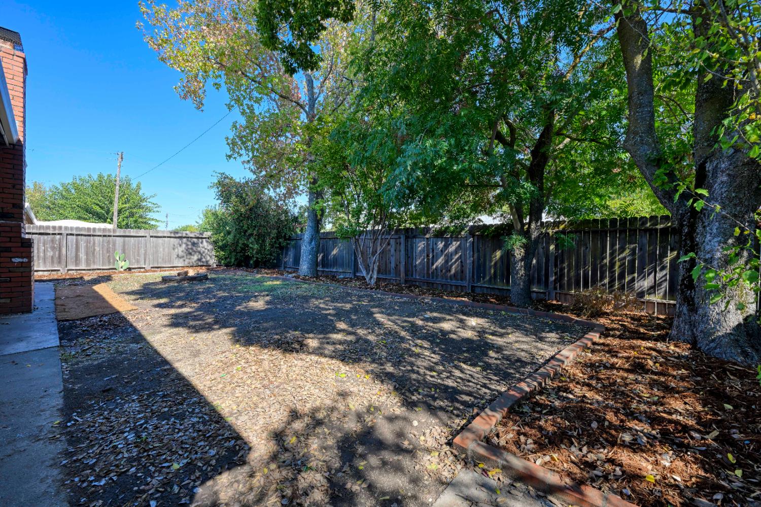 325 Archway Avenue Rio Linda, CA 95673 - Photo 23 of 29 a view of a backyard with large trees and wooden fence