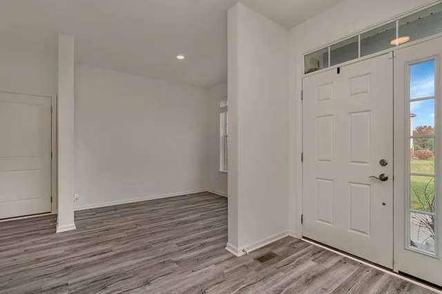 a view of an empty room with wooden floor and entrance