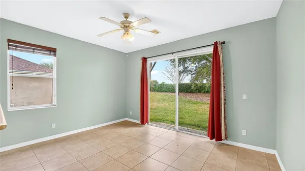 an empty room with wooden floor chandelier fan and windows
