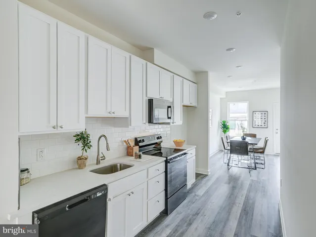 a kitchen with white cabinets sink and dining table