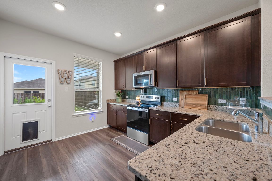 27 Pacific Loon Street Leander, TX 78641 - Photo 13 of 35 a kitchen with granite countertop a stove a sink and a microwave