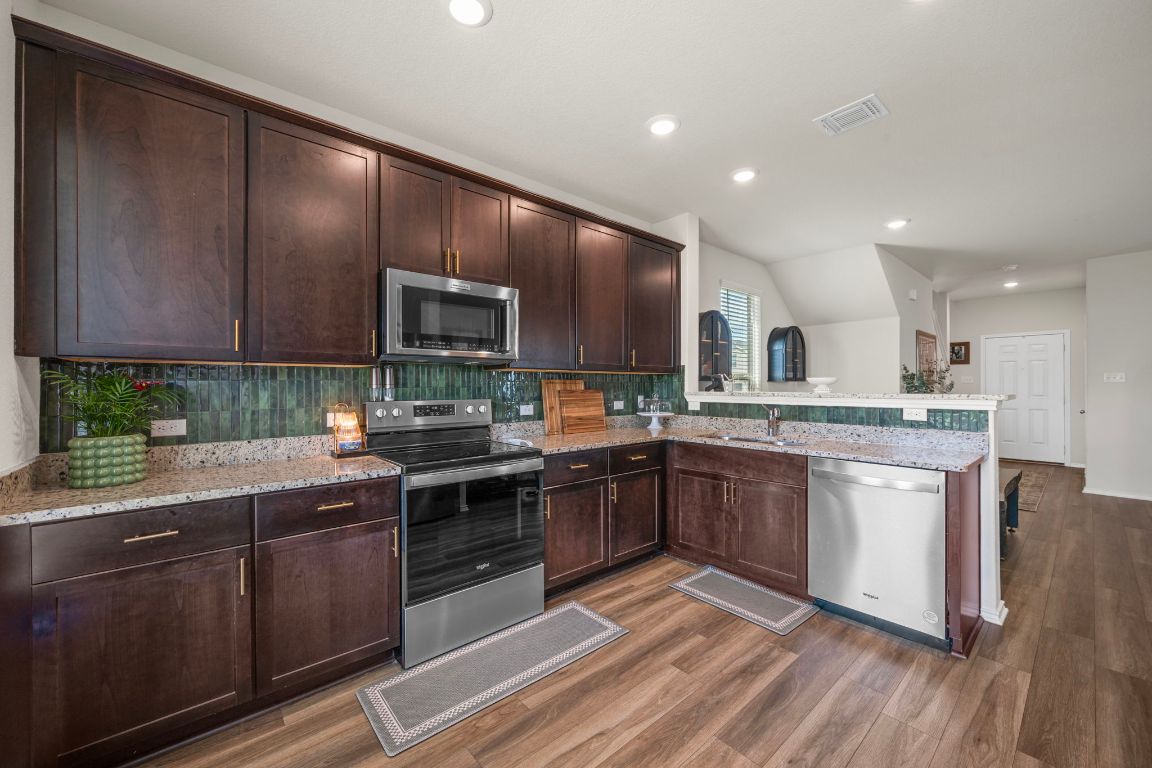 27 Pacific Loon Street Leander, TX 78641 - Photo 14 of 35 a kitchen with stainless steel appliances granite countertop wooden cabinets granite counter tops and a hard wood floors
