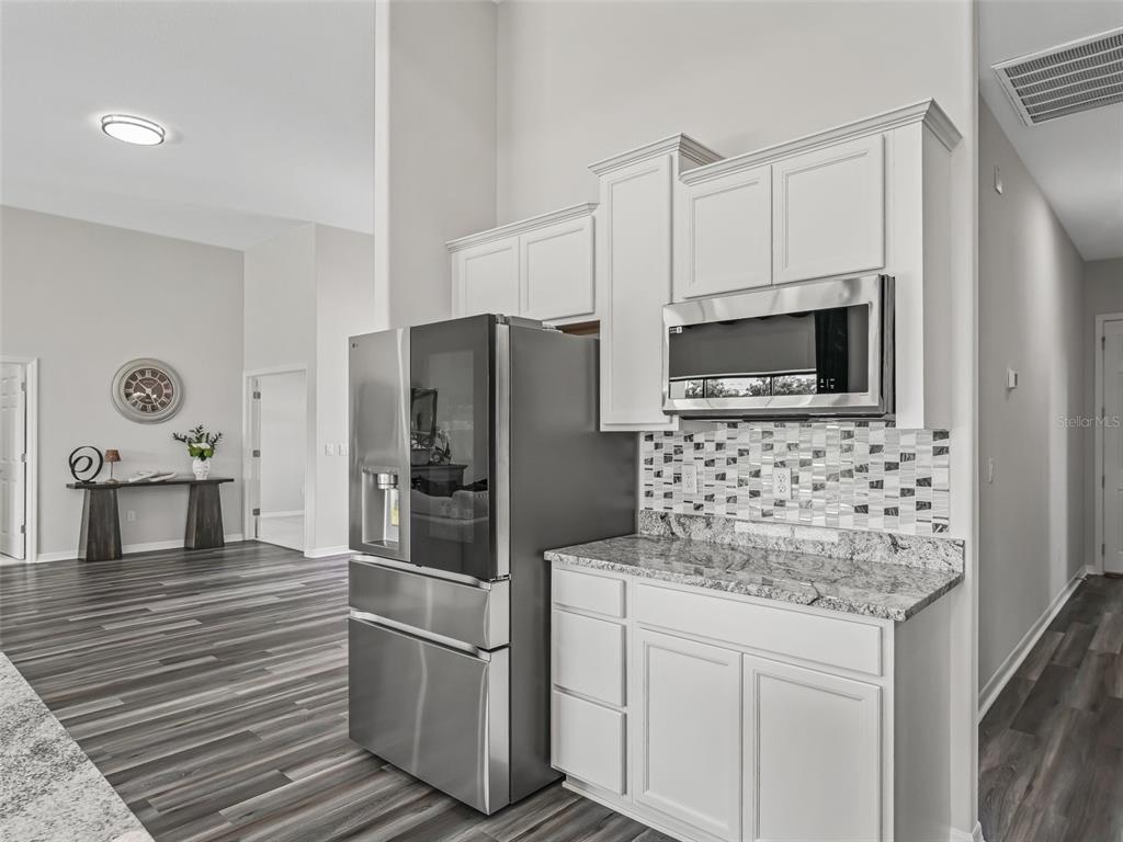 7041 Northeast 22nd Ct Road Ocala, FL 34479 - Photo 30 of 73 a kitchen with stainless steel appliances kitchen island granite countertop a refrigerator and a stove top oven