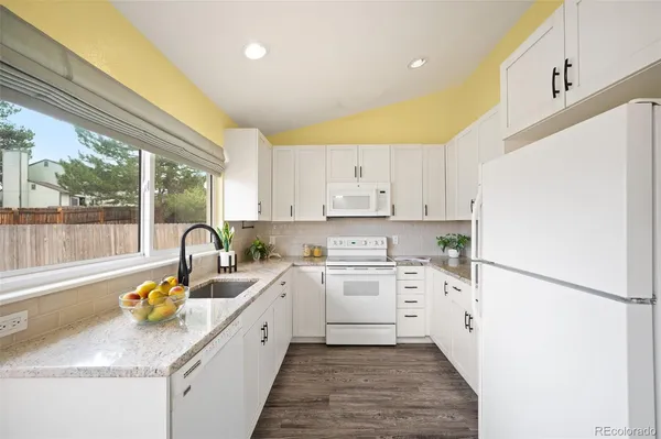 a kitchen with a sink white cabinets and white appliances