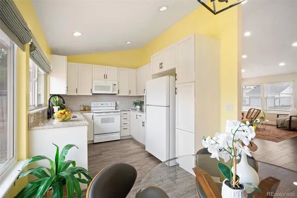 a kitchen with stainless steel appliances a white refrigerator a stove a sink dishwasher and white cabinets with wooden floor