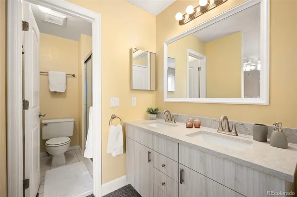 a bathroom with a granite countertop toilet sink and mirror