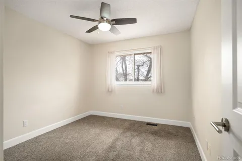 an empty room with a window and a fan