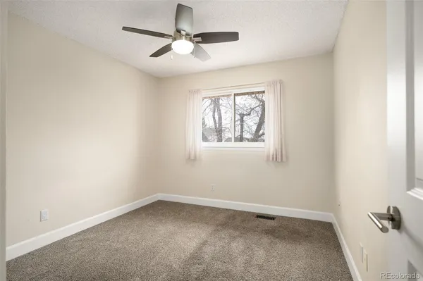 an empty room with a window and a fan