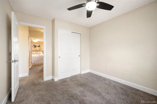 an empty room with a hallway and a chandelier fan
