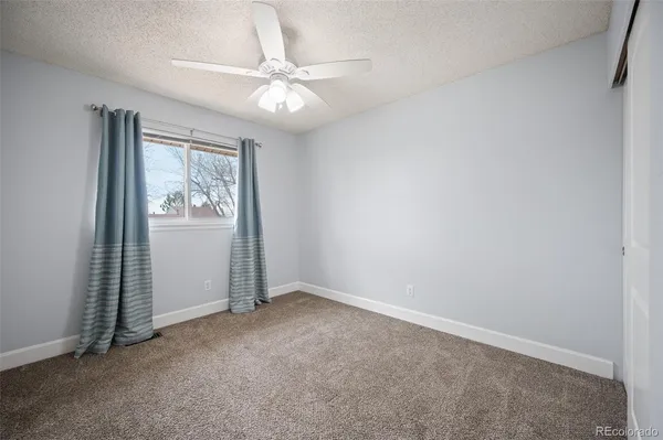 an empty room with windows and fan