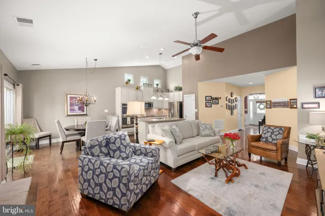 a open kitchen with stainless steel appliances granite countertop a stove a refrigerator a kitchen island a couches and chairs with wooden floor