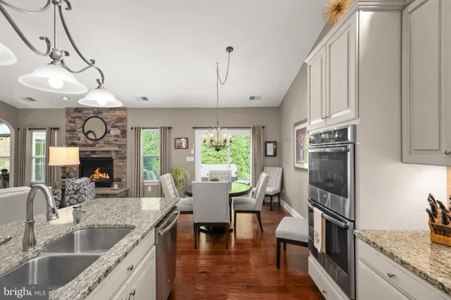 a living room with stainless steel appliances furniture a fireplace and a kitchen view