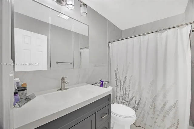 a bathroom with a sink a toilet and shower curtain