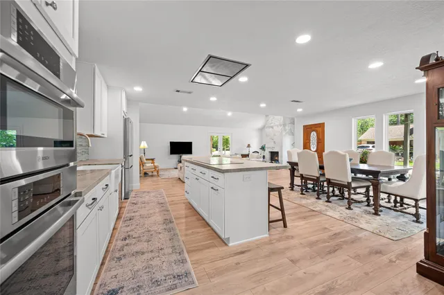 a large white kitchen with lots of counter space a sink appliances and a large window