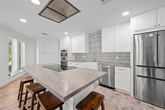 a kitchen with kitchen island a table chairs refrigerator and sink