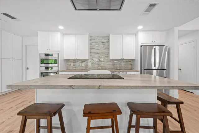a kitchen with stainless steel appliances granite countertop a sink and a refrigerator